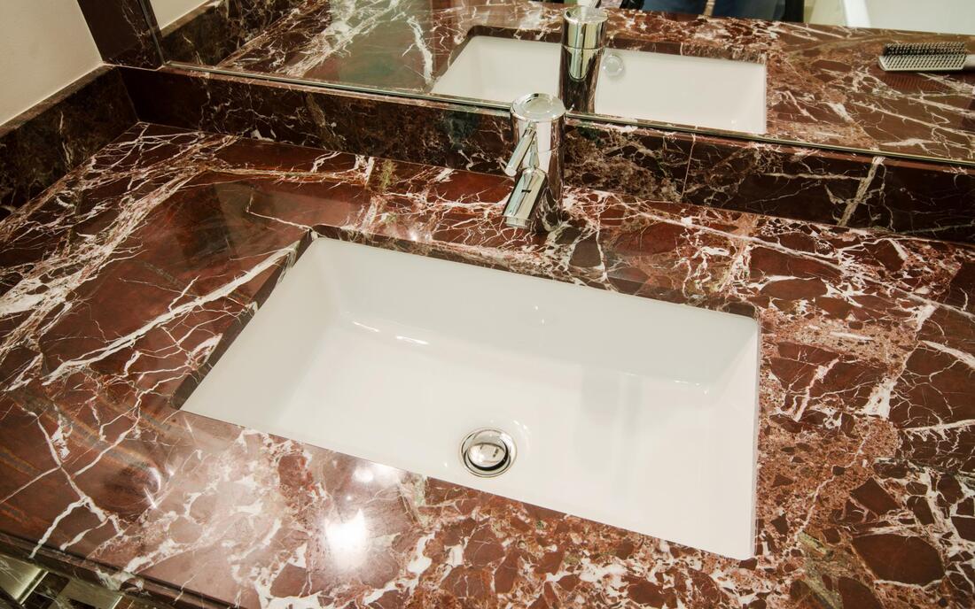 a sink with brown marbled  tiled